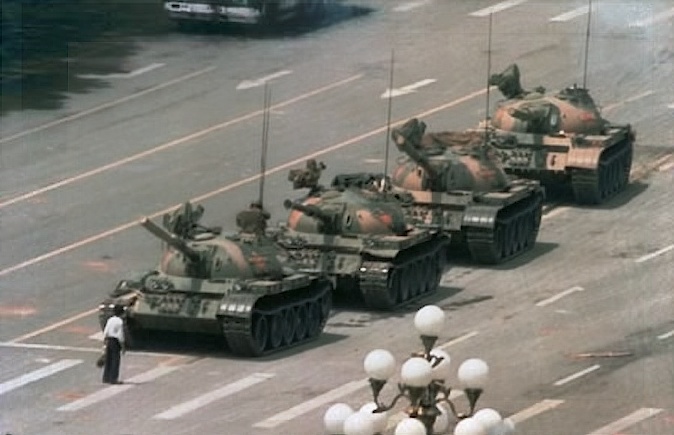 A picture of a man blocking several tanks by standing in front of them